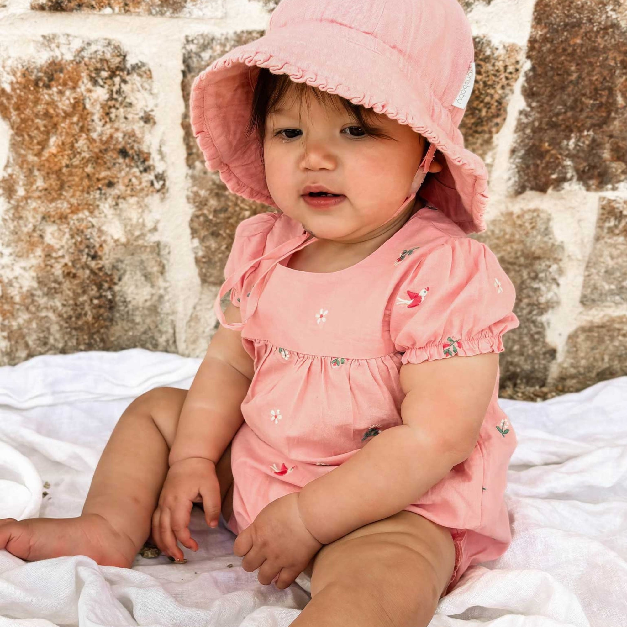 baby in a pink bodysuit made from organic cotton by purebaby organic