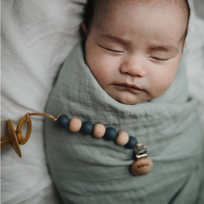 baby in mushie organic muslin swaddle blanket newborn